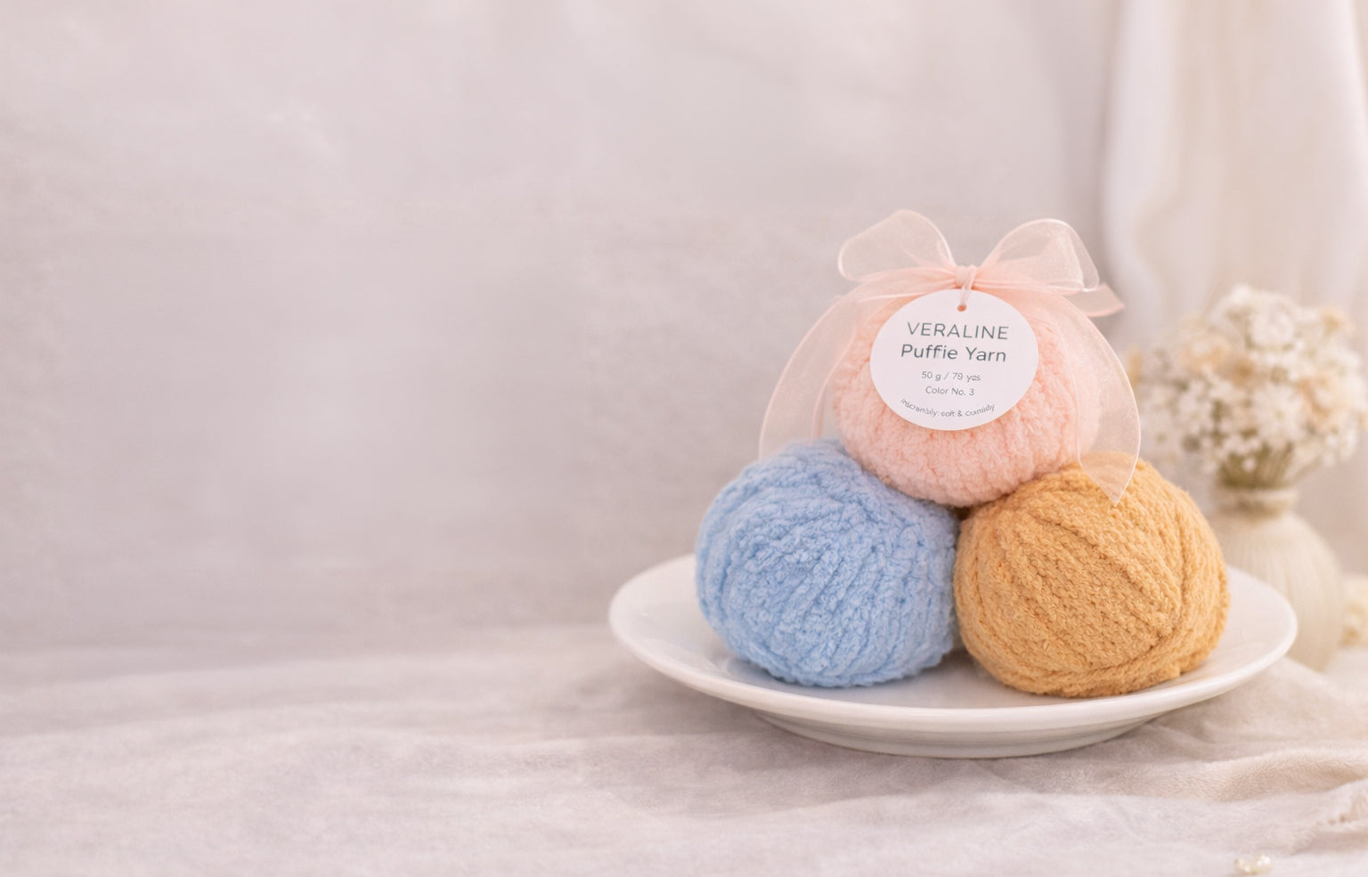 Three balls of yarn in pastel colors on a white plate with a neutral background